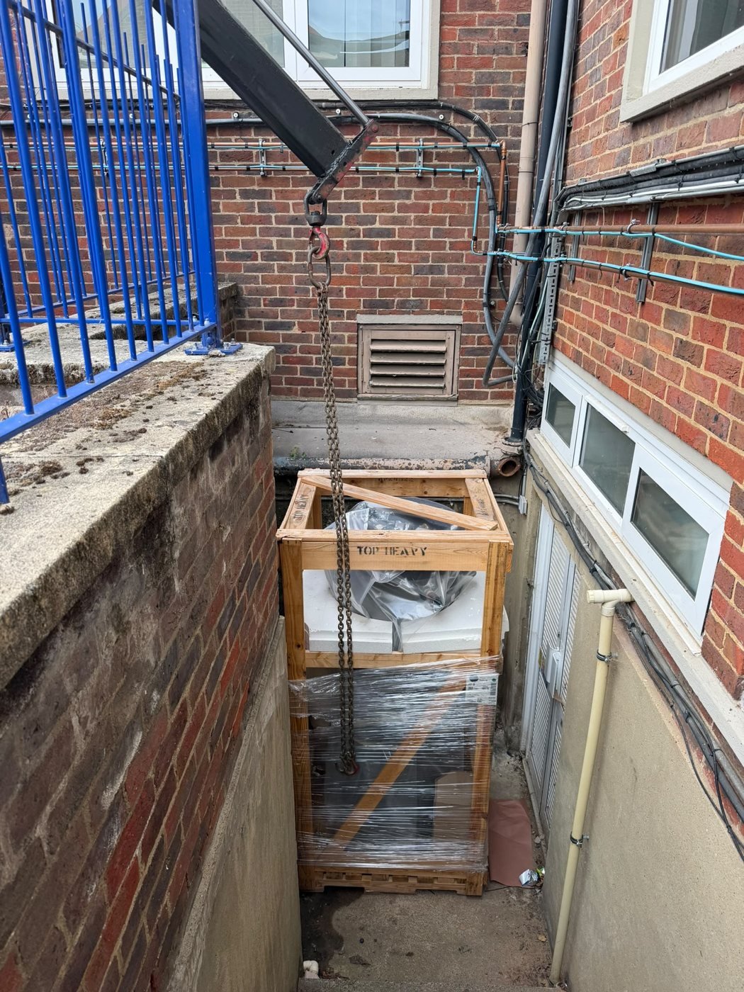 Crated equipment lowered beside a building