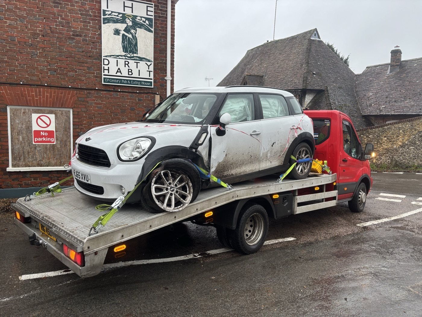 White compact car secured on a recovery truck